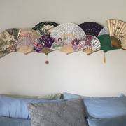 folding fans — A collection of decorative folding fans arranged above the bed.