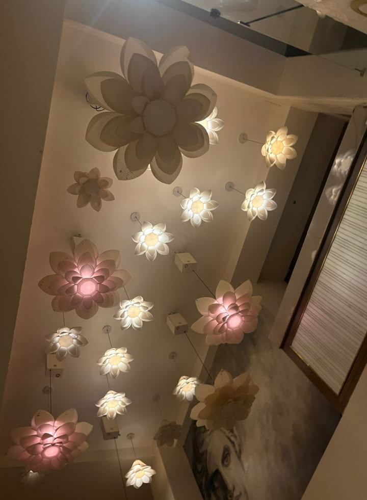 ceiling in bloom — ivory petals and soft pink light overhead.