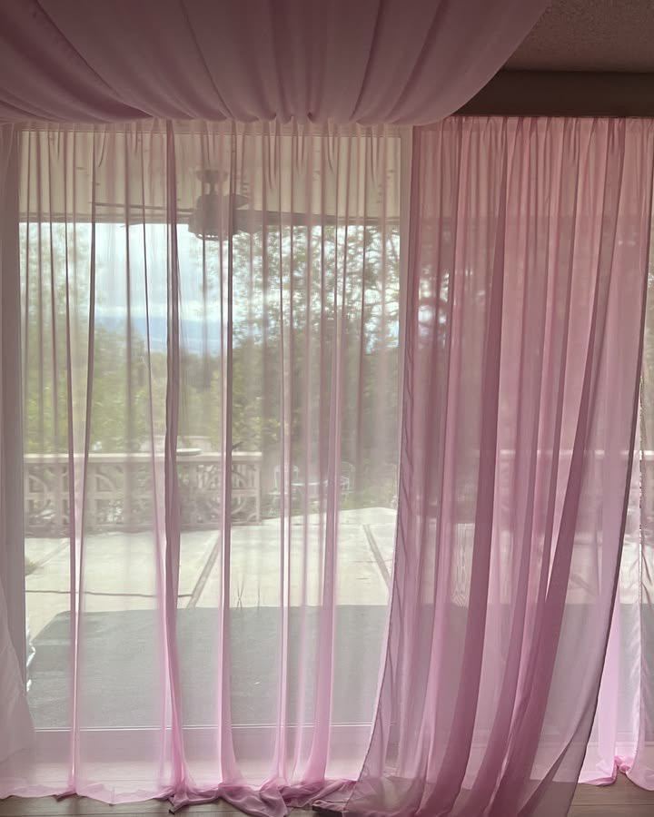Sheer pink curtains covering large windows, with matching fabric draped across the ceiling.