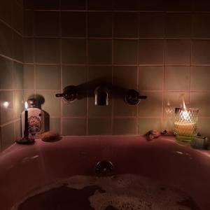 candlelit soak — pink tub, two flames, late hour — photo by Din Tanovic, Stockholm